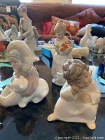 Photo showing all three Lladro figurines on a reflective surface, with the background showing a sofa and cushions.