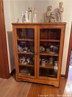 Front view of the wood display cabinet showing the two etched glass doors and contents inside.
