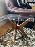 Side view of end table showing solid wood base and clear glass top in room setting