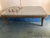 Full view of rectangular rattan coffee table with glass top showing overall condition and design.