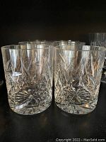 Close-up of 7 vintage pinwheel crystal rocks glasses showing intricate cut glass pattern and clarity, no chips visible.