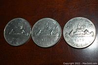 Reverse side of each of the three 1976 Canadian nickel dollar coins showing the Bluenose schooner design and inscriptions.