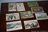 Photo showing 10 assorted postcards arranged on a wooden surface featuring vintage scenes and colorful illustrations.