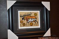 Full view of the professionally framed and matted art print featuring stylized moose and circular elements, showing the outer black frame with protective corner covers.