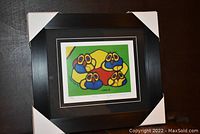 Full view of the framed fine art print titled "Owls" by Norval Morrisseau with protective corner covers on frame.