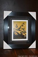 Framed and matted fine art print inside a dark wood frame with protective corner covers.
