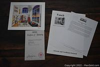 Photo showing the unframed print alongside certificate of authenticity and supporting documents.