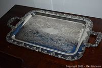 Full view of rectangular silver plated serving tray with ornate engraved pattern and detailed border with handles on each side