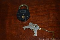 Image showing the top view of the round Yale padlock with attached keys on a wooden surface.