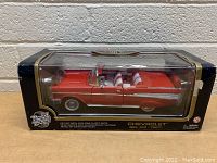 Front view of diecast 1957 Chevrolet Bel Air in original packaging showing red convertible with white interior.