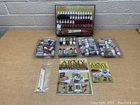 The full set displayed on a table including paint trays, brushes in pouch, instructional booklets, and the original set box showing the Army Mega Paint Set label.