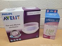 Photo showing Philips Avent microwave steam sterilizer box and Dr. Brown's feeding set box side by side.
