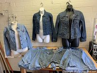 Photo showing three denim jackets on mannequins and six more laid flat on table.