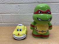 Front view of Teenage Mutant Ninja Turtle and yellow taxi ceramic coin banks