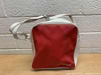 Front view of vintage Columbia shoulder bag showing red front panel with white edges and Columbia logo.