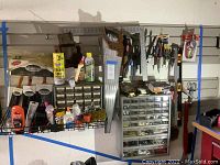 Wide shot of assorted hardware and tools arranged on wall-mounted racks and organizers in a garage setting