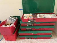 Stacked red and green storage bins filled with holiday items including wrapping paper and decorations.