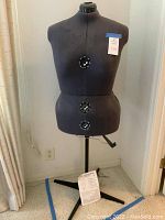 Front view of black Dritz TwinFit 8 section adjustable dress form on tripod stand with adjustment crank below the torso.