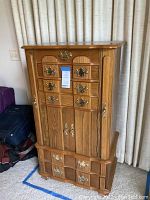Full front view of oak jewelry cabinet with drawers and side compartments closed