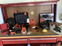 Wide view of all power tools and accessories placed on a red workbench with pegboard back.