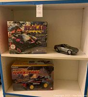 Shelf showing boxed RadioShack Bedlam and Hurricane radio controlled car boxes, with silver model car beside the Bedlam box