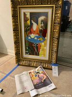 Full view of framed serigraph leaning against wall with certificate of authenticity in front