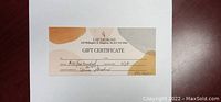 Photo of the $100 gift certificate from LSP Designs showing store information and authorized signature.