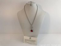 Front view of the necklace displayed on white bust showing the silver-tone chain and red crystal pendant.