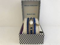 Five stretch bracelets displayed on a white bracelet holder inside a Bella Perlina branded box with black and white zigzag pattern.