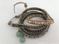 Photo of the leather wrap bracelet coiled showing multiple strands of beads in turquoise, cream, mint, green, and crystal, with tan leather threading and a tied clasp.