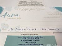 Gift certificate paper with 'Aura Skin + Soul Care' branding and appointment details handwritten on it, displayed flat to show the entire certificate.