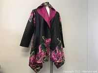 Front view showing black floral textured fabric with a contrasting fuchsia tuxedo collar.