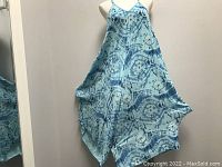 Front view of turquoise and blue batik romper with thin straps on mannequin. Shows loose fit and V-neckline.