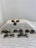 Six pairs of kids sunglasses displayed with tags attached, 3 black tone and 3 gold tone.