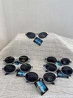 Overview of six pairs of oval sunglasses with silver-tone frames and dark lenses, each tagged Blue Band.