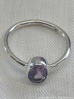 Front angle of sterling silver ring featuring a round amethyst stone showing rich deep purple color.