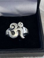 Close-up of sterling silver Om symbol ring in black jewelry box, showing front view of the symbol and band.
