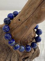 Close-up of lapis lazuli beads on the stretch bracelet against a wood background.