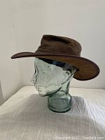 Front angle of the brown leather Australian bush hat displayed on a glass head form.