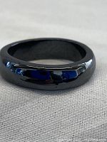 Close-up image of a glossy black magnetic hematite ring with smooth, rounded profile, showing reflective surface and polished finish.