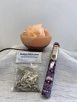 Image showing lit Himalayan salt lamp alongside unopened packet of Buffalo White Sage and unopened lavender incense pack in purple wrapper.