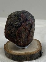 Side view of raw garnet stone on wooden base