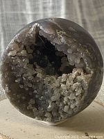 Front view of the polished Grape Agate stone showing the open geode cavity with small botryoidal crystal formations inside, illustrating the natural internal structure of the stone.