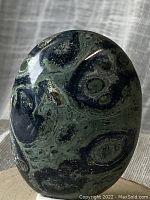 Close up view of the oval polished Kambaba Jasper stone showing its fossilized algae patterns and coloration.