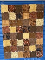 Full view of patchwork blanket showing assorted fabric squares in shades of brown, beige, cream, with autumn patterns including leaves and plaid.