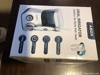 Photo of the front of the ABOX oral irrigator box showing product image and features such as pressure setting, timer start, 360-degree rotating tip, and waterproof charger.