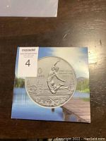 Photo of the coin box packaging showing the coin image with lake and dock background and denomination details.