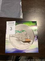 Photo of the coin and its colorful certificate showing the polar bears sledding design.