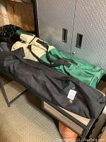 Photo showing three camping chairs packed inside their carrying bags lying on a bench or table.