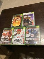 Photo of all five Xbox game cases on dark brown table surface